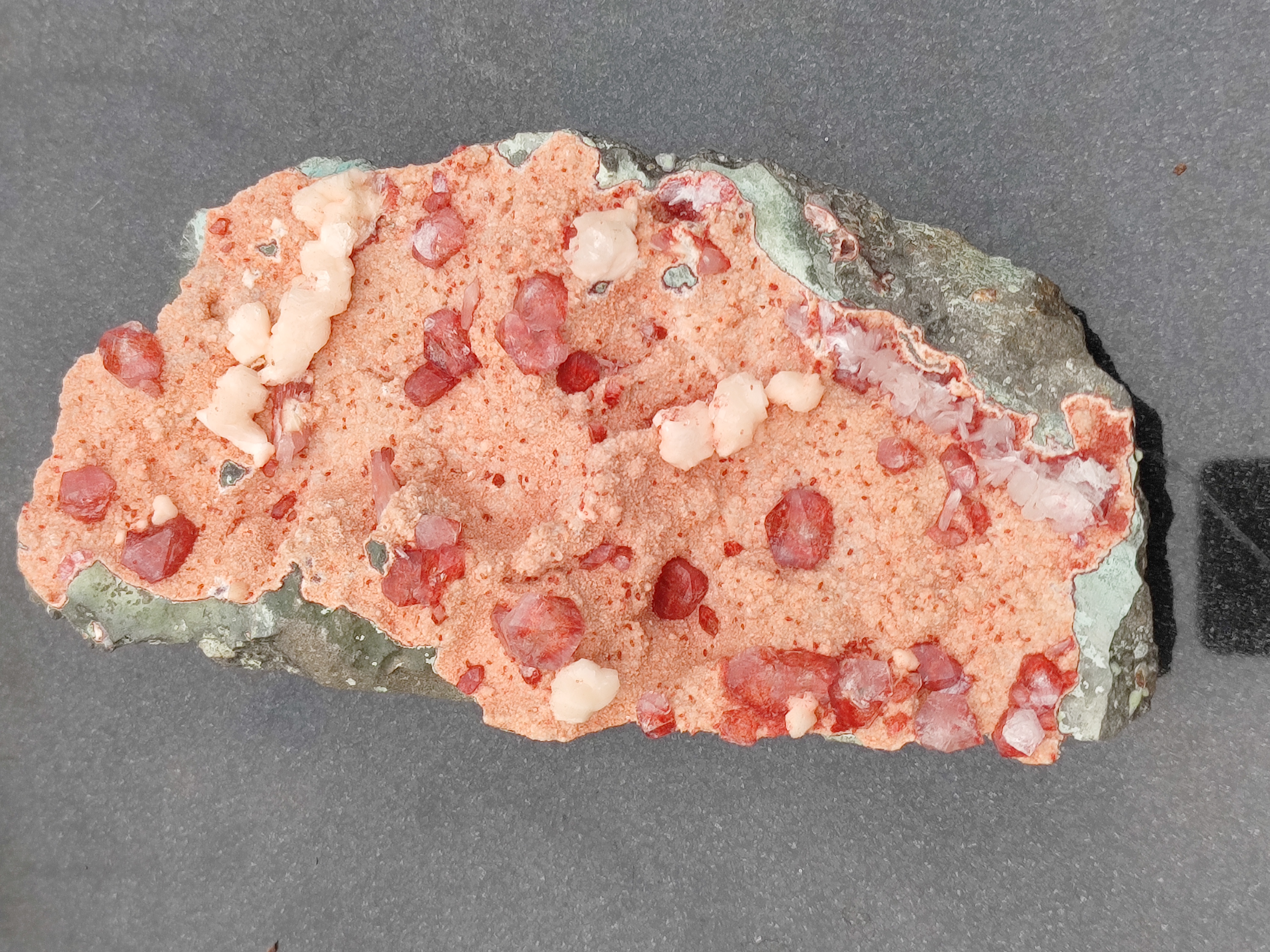 Crystalline Tutti Frutti Icecream
Nature’s Sweetest Sculpture in Stone

A marvel of mineral magic, the Crystalline Tutti Frutti Icecream is a naturally occurring gemstone cluster that resembles a scoop of the beloved Italian dessert—bursting with color, texture, and joyful energy. Formed over millennia, this specimen is a celebration of Earth’s playful artistry, blending coral-pink rhyolite, ruby-red garnet-like crystals, and creamy white chalcedony nodules into a composition that feels both delicious and divine.

💎 Visual Composition

Coral-pink rhyolite base with a granular, frosted texture

Scattered ruby-red translucent crystals, reminiscent of garnet or spinel, glistening like candied fruit

Smooth, rounded white chalcedony nodules, adding creamy contrast and balance

Encased in a rugged greenish-gray border, grounding the vibrant interior with earthy elegance

🔮 Metaphysical Resonance

Stimulates joy, creativity, and emotional warmth

Balances heart and sacral chakras, encouraging playfulness and passion

Ideal for uplifting spaces, inspiring artistic flow, and celebrating inner light

🌿 Suggested Placement Display in creative studios, healing spaces, or joyful corners of your home. Its candy-like appearance and radiant energy make it a perfect centerpiece for those who seek beauty with meaning.

🧘‍♀️ Recommended Ritual Hold the stone during moments of self-expression or celebration. Let its vibrant hues remind you of life’s sweetness and the magic of being fully present.